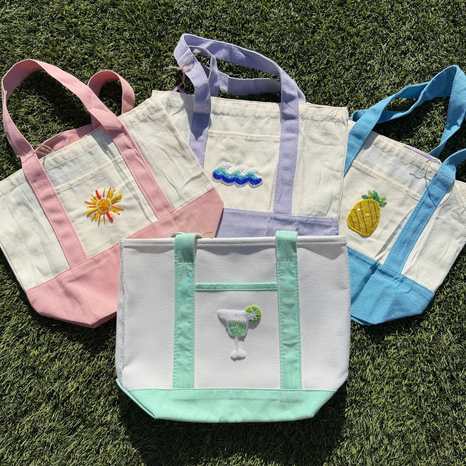 Set of four embroidered tote bags on grass