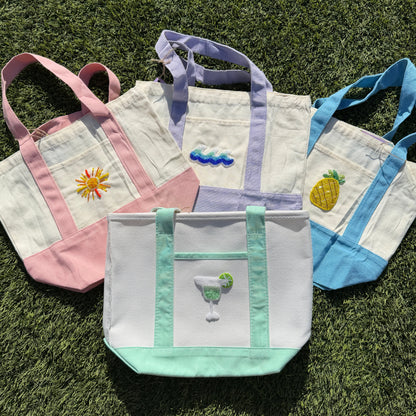 Set of four embroidered tote bags on grass