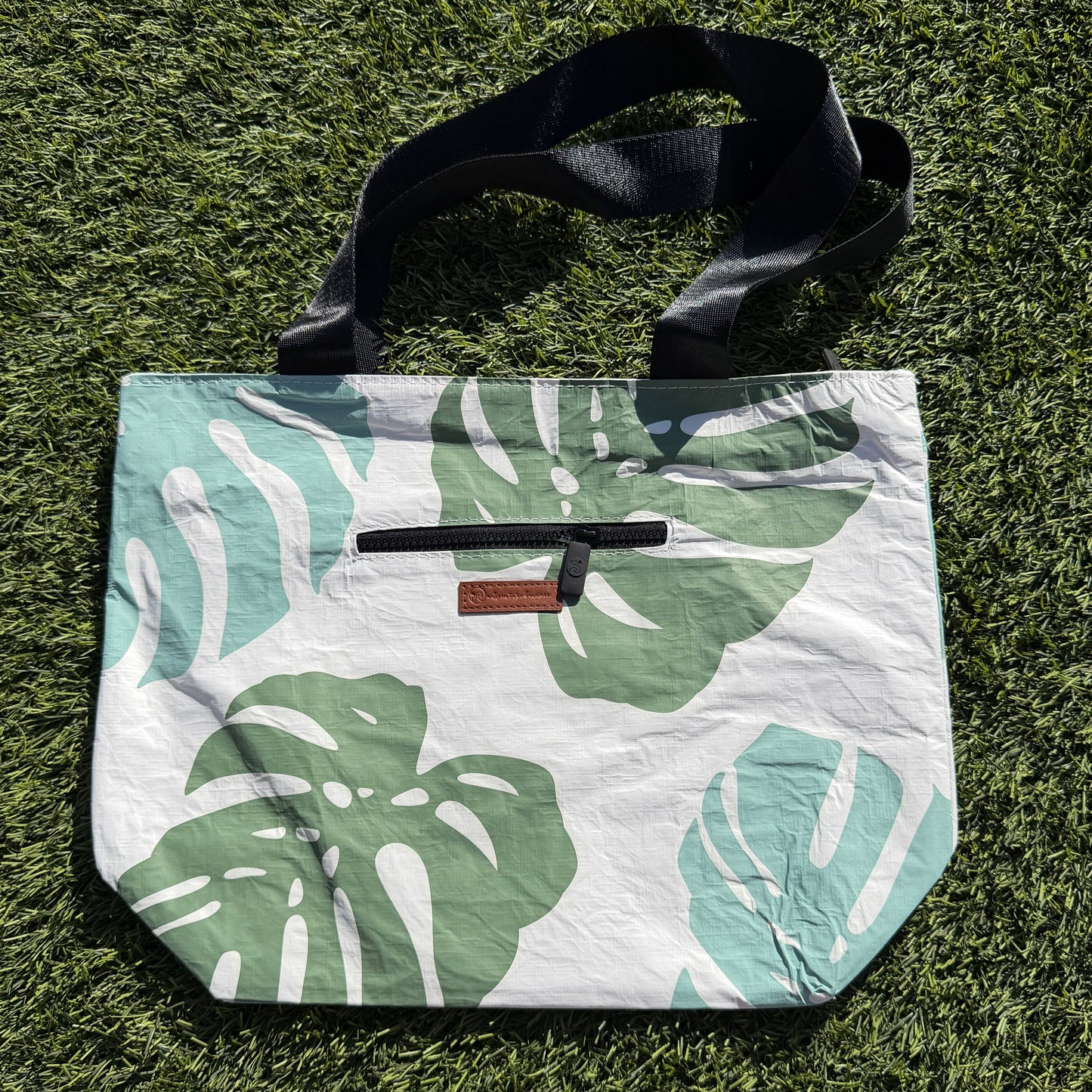 Floral-patterned bag with a strap on grass