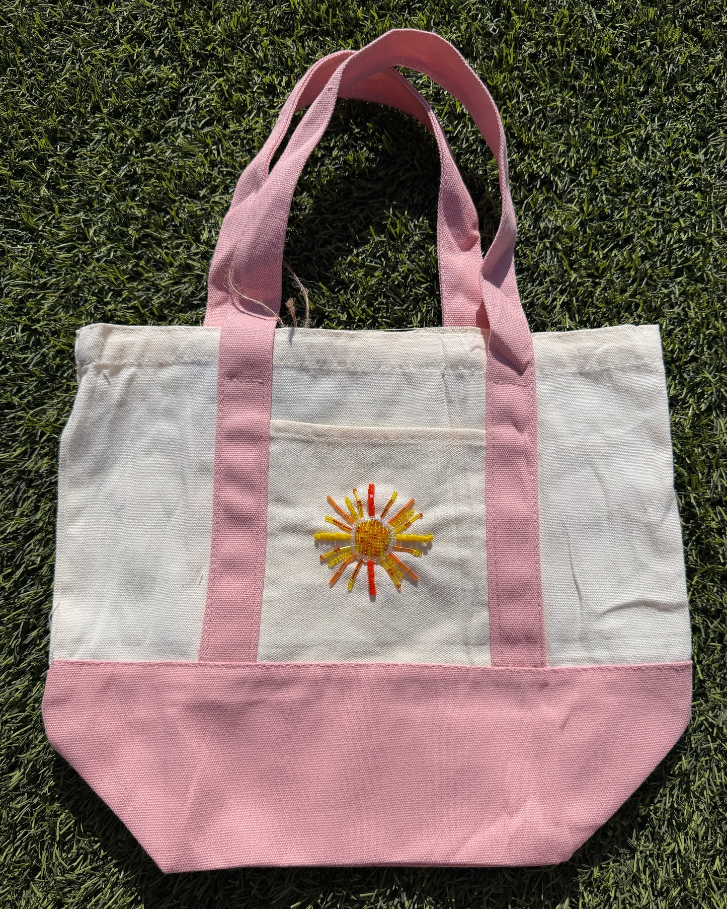 Tote bag with a sun design on a grassy surface
