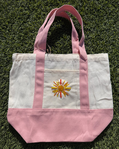 Tote bag with a sun design on a grassy surface