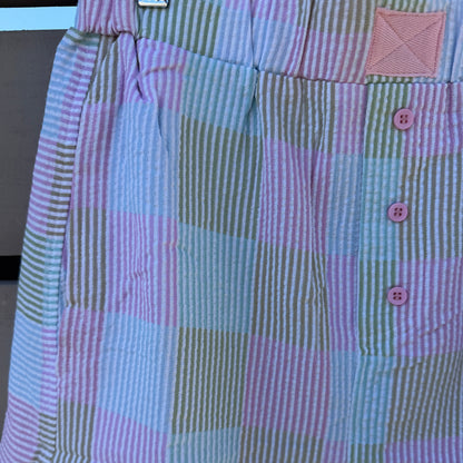 Close-up of a checkered shorts with pink buttons on a neutral background