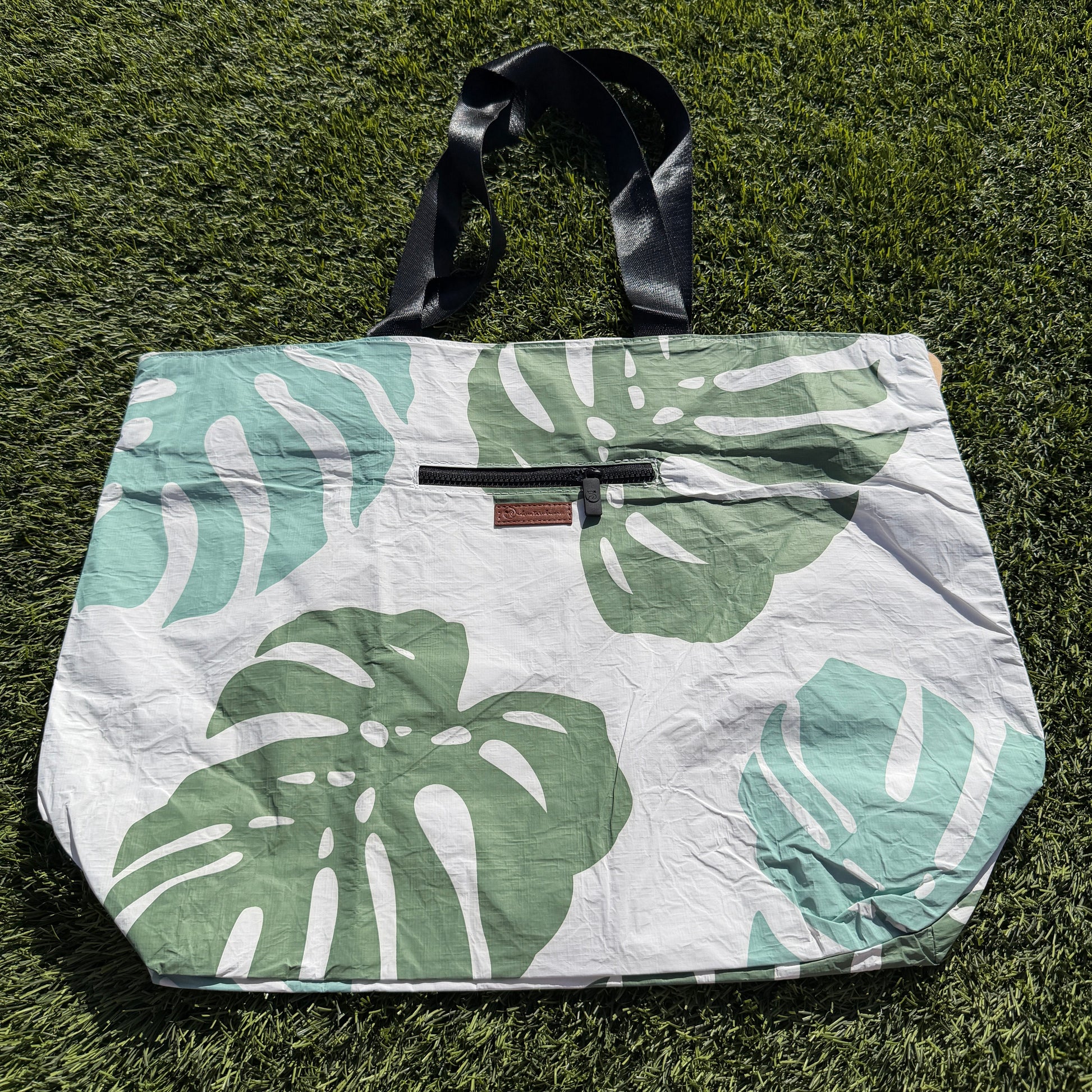 Tote bag with green leaf pattern on grass