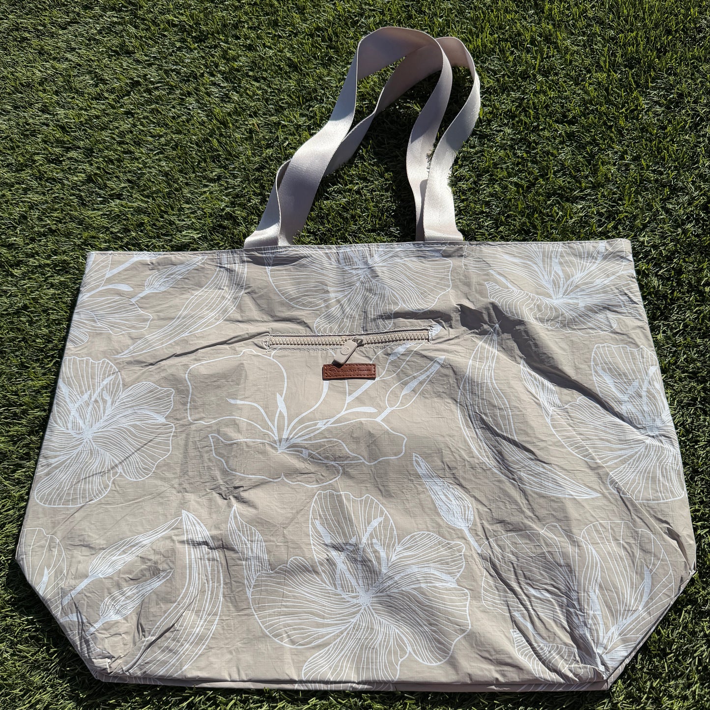 Floral-patterned tote bag on a grassy background