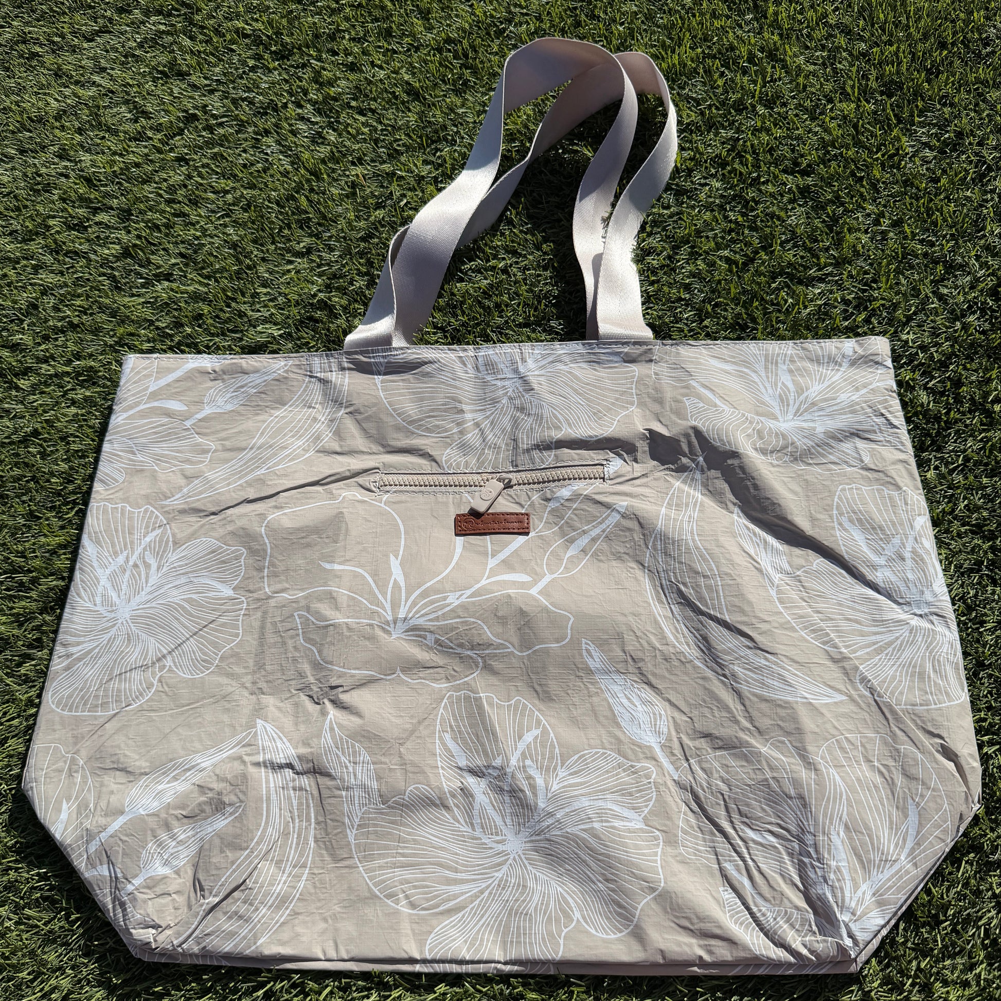 Floral-patterned tote bag on a grassy background