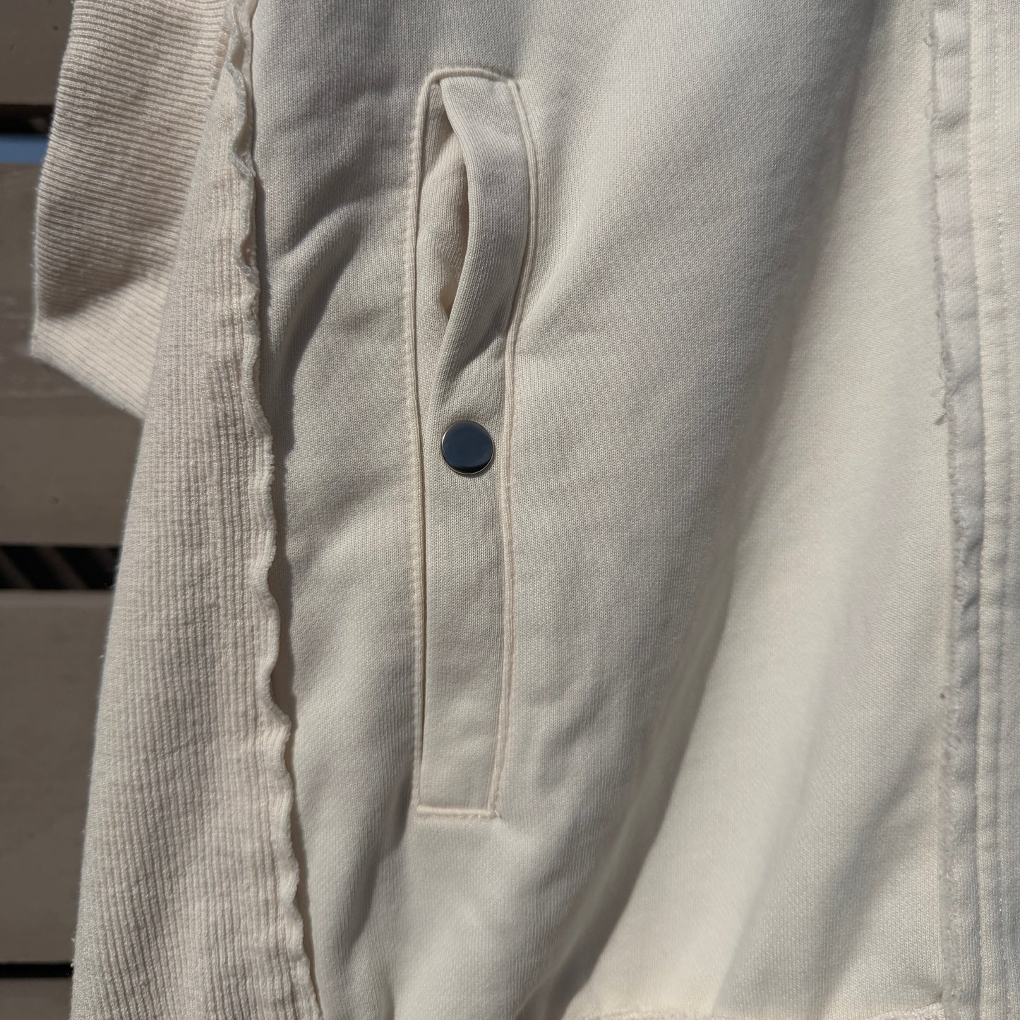 Close-up of a white jacket with a button on a blurred background
