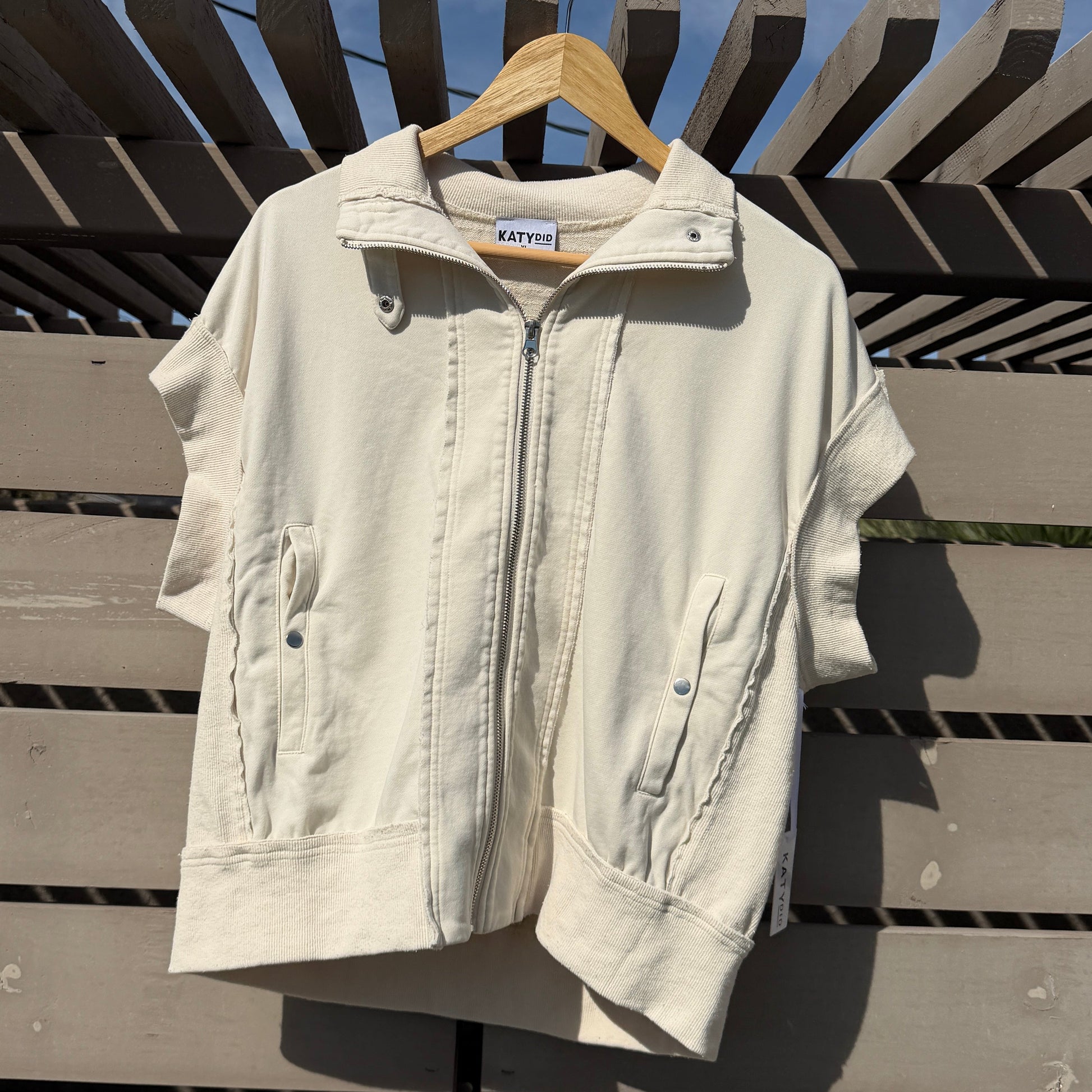 White jacket on a hanger against a wooden fence with blue sky background