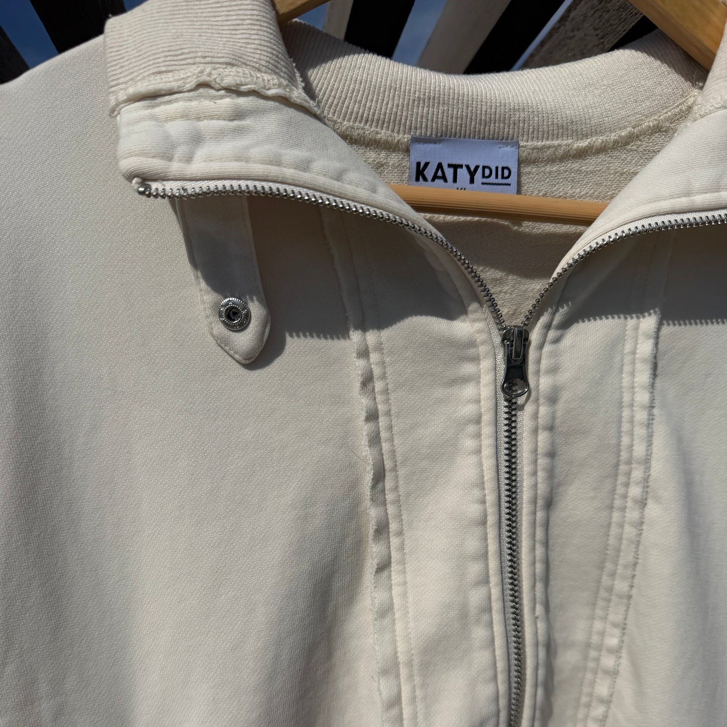 Close-up of a beige jacket with a zipper and 'KATYDID' label.